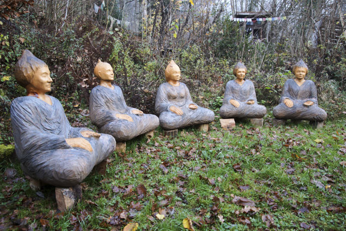 Cinq sculptures de Monik, bouddhas méditants dans une clairière à Sapois.